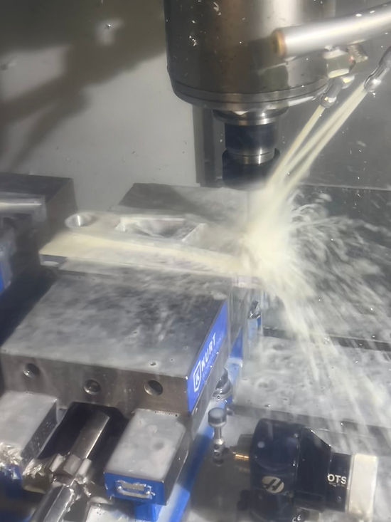 CNC mill cutting a brake pedal part under coolant